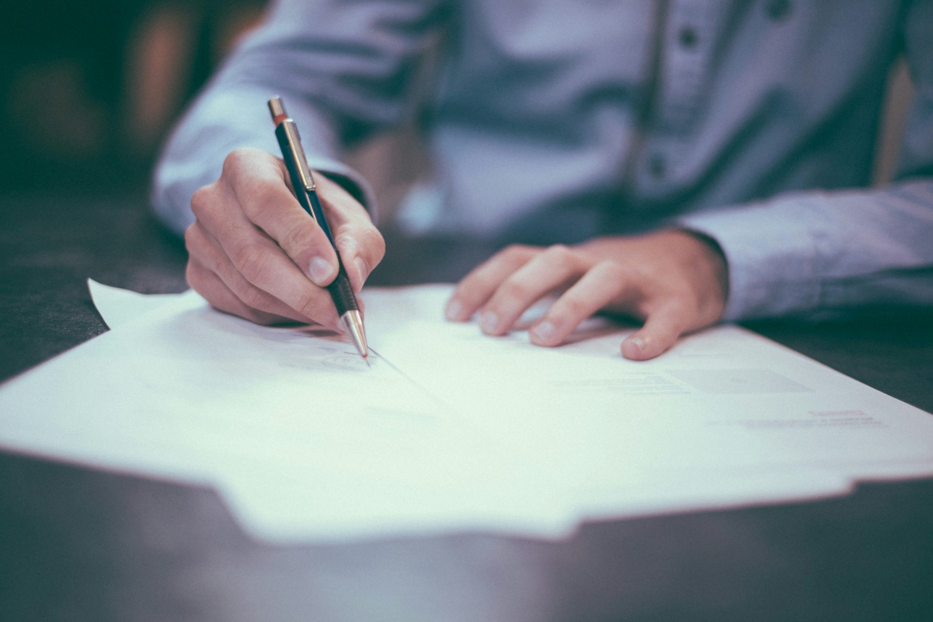 Man signing documents with focused attention.